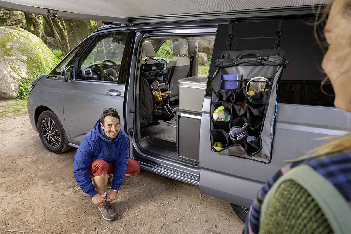 Ein Mann kniet vor einem Camper