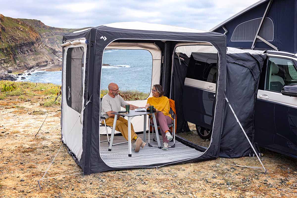 Ein Paar sitzt im Vorzelt vor einem Camper