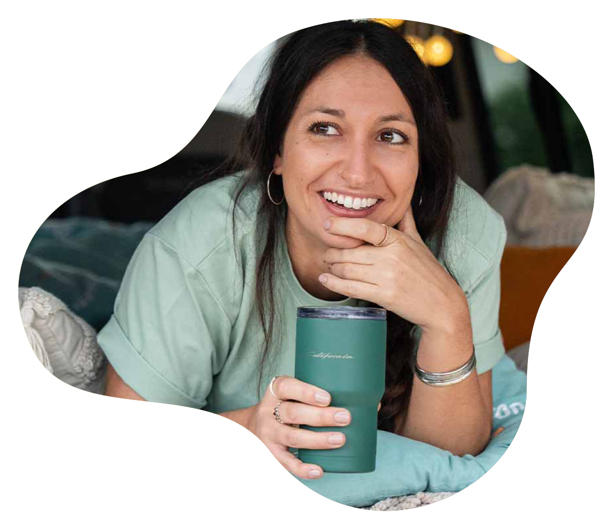 Eine Frau mit Becher liegt im Camper